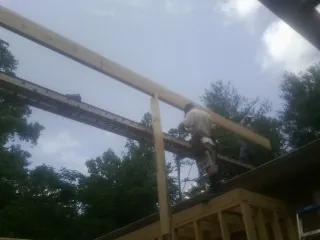 Carpenter setting a ridge beam over a new addition frame — Ice Dam Removal by Roofing Brothers in Louise