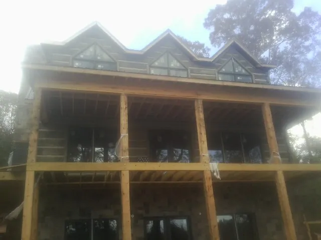 Dormers and porch framing on a large log home under construction — Roof Coating work by our crew in Louise