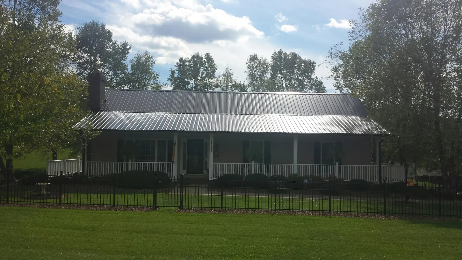 Gray metal roof on a brick ranch with a full width front porch — Gutter Guard Installation work by our crew in Louise