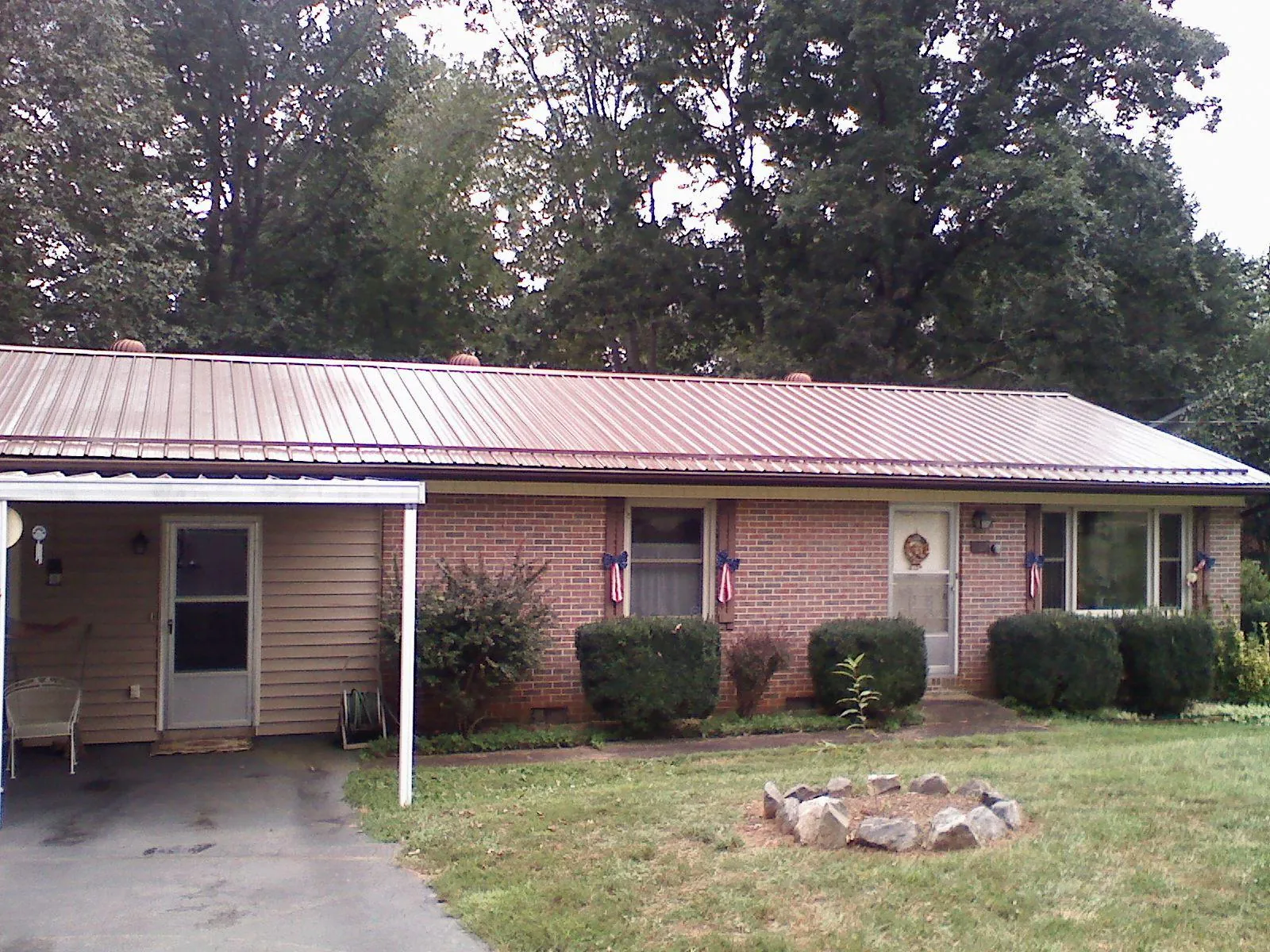 Bronze metal roof and carport on a brick ranch home — Roof Repair work by our crew in Louise