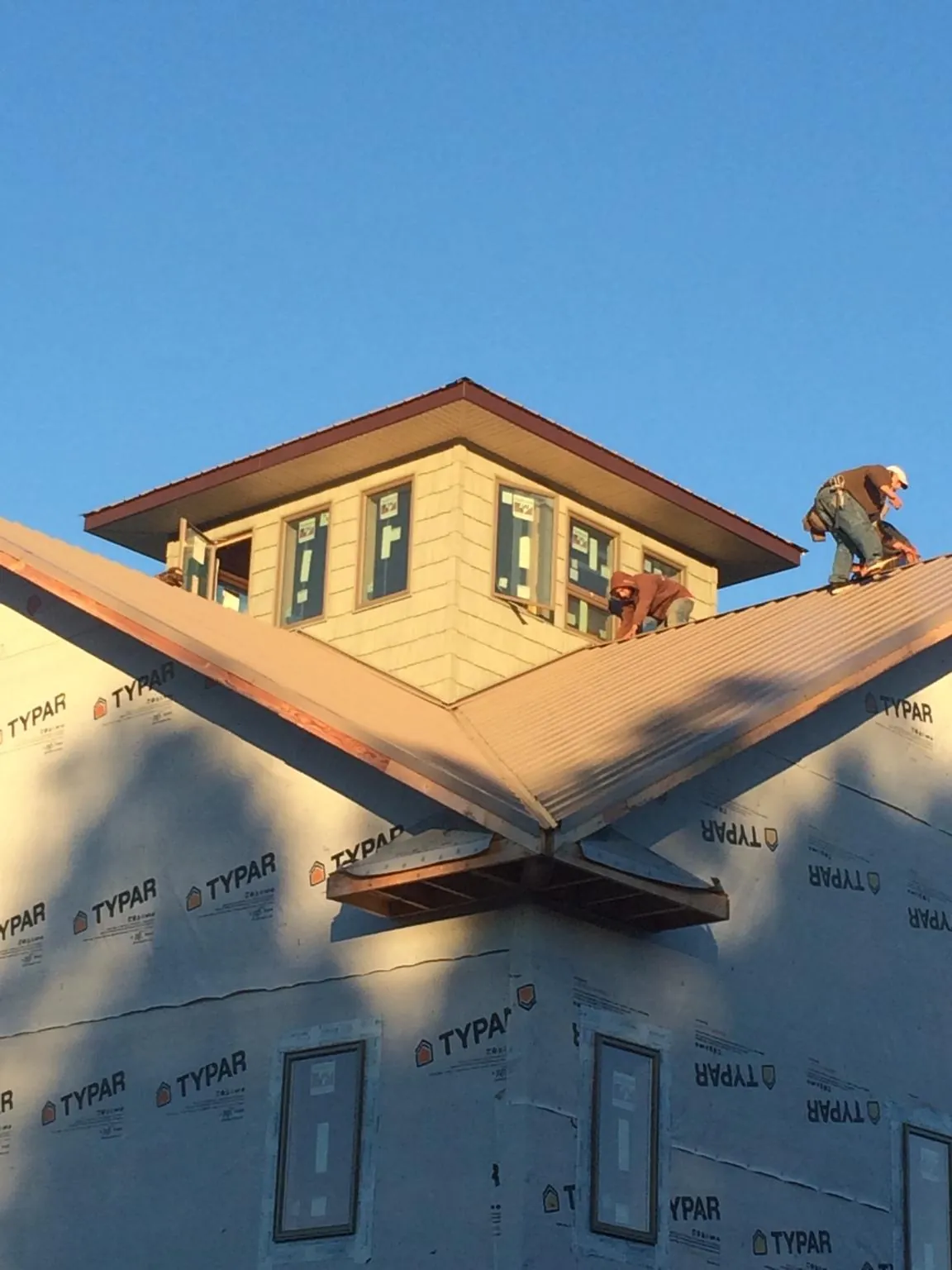Roofers working around a rooftop cupola on a new metal roof at sunset — Roof Waterproofing in Louise by Roofing Brothers